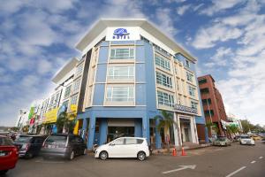 un edificio azul y blanco con coches aparcados en un aparcamiento en Pantai Regal Hotel, en Kuantan