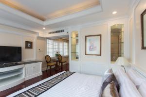 a bedroom with a bed and a flat screen tv at The Lek Aree in Bangkok