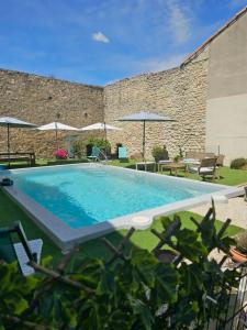 a swimming pool with chairs and umbrellas next to a building at Partie de villa in Velleron