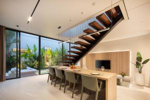 a dining room with a long table and a staircase at Echo Beach Villas 6 in Canggu