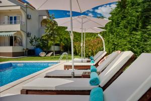 a group of lounge chairs with an umbrella next to a pool at Villa MontAnja in Herceg-Novi
