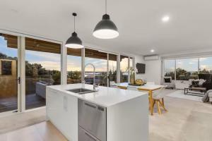 a kitchen and living room with a table and chairs at Ocean view Designer Standalone Villa Big Deck in Auckland +16 photos