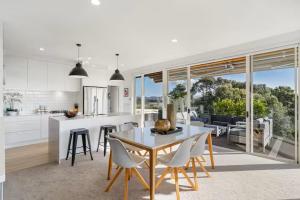 a kitchen and dining room with a table and chairs at Ocean view Designer Standalone Villa Big Deck in Auckland