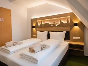 a bedroom with two white beds with towels on them at Pension am Markt in Wurzen