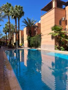 a swimming pool in front of a building with palm trees at Riad Anbar in Marrakesh