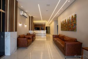 a lobby with brown leather couches and a kitchen at Rede Andrade Itabuna in Itabuna