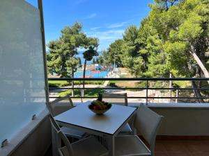 a table and chairs with a bowl of fruit on a balcony at Pine Resort by Residence in Strožanac