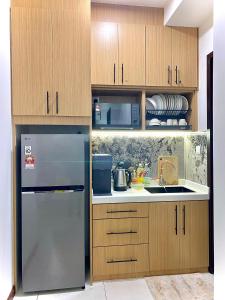 a kitchen with wooden cabinets and a stainless steel refrigerator at K Avenue by FRHome, 2 bedroom apartment within 5 min to KKIA airport in Kota Kinabalu
