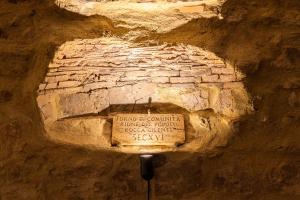 a stone wall with a sign in a cave at Rocha Suites in Rocca Cilento