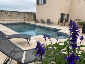 a swimming pool with chairs and purple flowers at chambre d'hotes les cigales in Comps +41 photos