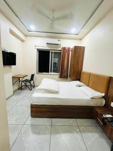 a bedroom with a bed and a table and a window at Hotel Nakshatra in Guna
