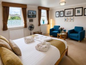 a bedroom with a bed and two blue chairs at Riviera Lodge Hotel in Torquay +72 photos