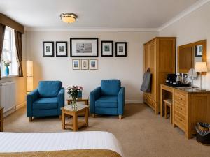 a hotel room with two blue chairs and a desk at Riviera Lodge Hotel in Torquay