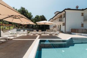 a swimming pool with umbrellas and chairs and a house at Rezidenca Ortus in Ankaran