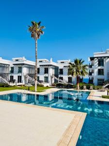 a swimming pool with a palm tree in front of a building at Atlantis Malibu by Carrington in Kyrenia
