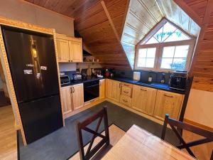 a kitchen with wooden cabinets and a black refrigerator at Apartament Łostówka in Łostówka
