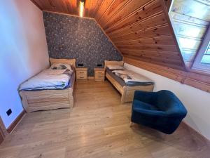 a room with two beds and a blue chair at Apartament Łostówka in Łostówka