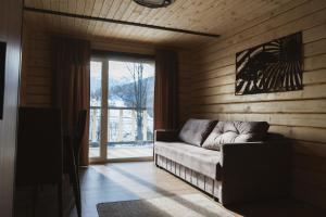 a living room with a couch in front of a window at Tri houses in Podobovets