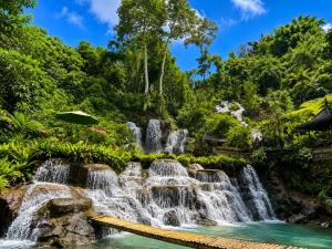 a waterfall in a garden with a pool at Kidupa Villa - 2 BR Private Pool & Rice Field View in Ubud