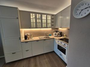 a kitchen with white cabinets and a clock on the wall at MareTime - inkl Wäschepakete, 50m zum Strand in Pelzerhaken
