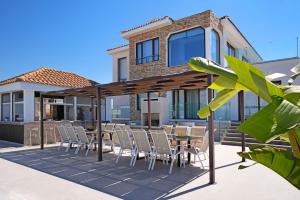 a patio with chairs and tables and a house at Cape Serenity Mansion in Ayia Napa