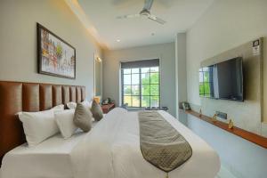 a bedroom with a large white bed with a flat screen tv at The Leaf in Ludhiana