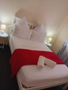 a large white bed with a red blanket and pillows at Faranie Guesthouse in Oudtshoorn