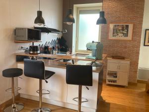 a kitchen with a counter with three bar stools at Duplex de la République in Millau +4 photos