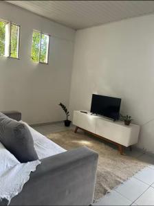 a white room with a bed and a tv at Lar sossego Itabuna in Itabuna