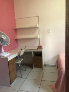 a room with a desk with a fan and a pink wall at Lar sossego Itabuna in Itabuna