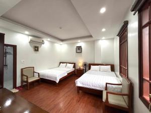 a hotel room with two beds and a chair at Sam Son Golden Dream Hotel in Sầm Sơn
