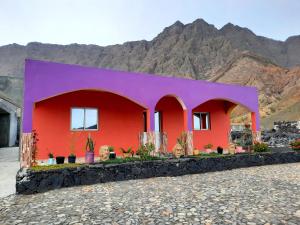 a red and purple house with mountains in the background at Casa Pirinha in Portela
