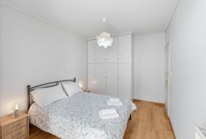 a white bedroom with a bed and a chandelier at Moschato-Niarchos modern apartment in Piraeus