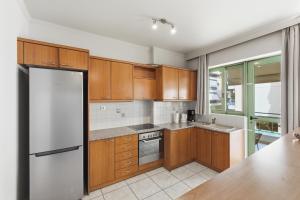 a kitchen with wooden cabinets and a refrigerator at Moschato-Niarchos modern apartment in Piraeus