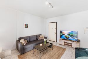 a living room with a couch and a flat screen tv at Moschato-Niarchos modern apartment in Piraeus