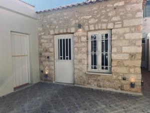 a stone house with a white door and windows at Anna home Elafonisos in Elafonisos