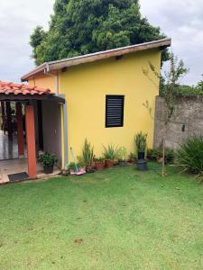 a yellow house with plants in a yard at Recanto Pedrita in Pedreira