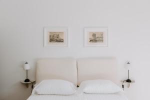 a bedroom with two white beds with two pictures on the wall at Casa Vacanze Bottasso 68 in Terracina