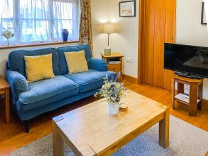 a living room with a blue couch and a coffee table at Corner Cottage in Saxmundham +13 photos