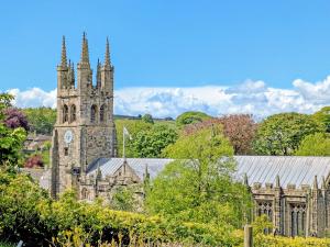 an old building with a clock tower and a church at Parsley Cottage in Tideswell