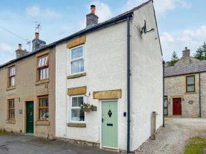 an old brick house with a green door at Parsley Cottage in Tideswell