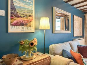 a living room with a couch and a table with a vase of flowers at Parsley Cottage in Tideswell +12 photos