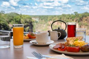 a table with two plates of food and two glasses of juice at Miombo Mews in Victoria Falls