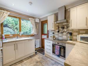 a kitchen with white cabinets and a sink at Lochside View in Lochearnhead