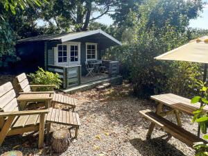 a picnic table and benches in front of a shed at Rosehill in Truro