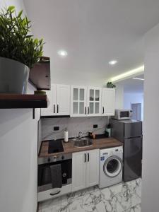 a kitchen with white cabinets and a sink and a dishwasher at The Cosy House in Kyustendil