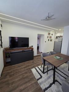 a living room with a table and a flat screen tv at The Cosy House in Kyustendil