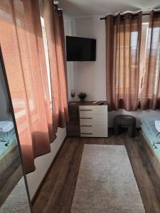 a bedroom with orange curtains and a dresser and a television at The Cosy House in Kyustendil