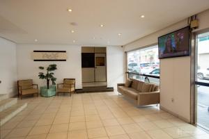 a lobby with a couch and a tv in a building at Rede Andrade Royal in Itabuna