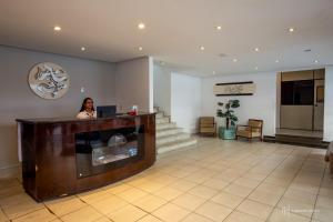 a woman sitting at a reception desk in a lobby at Rede Andrade Royal in Itabuna